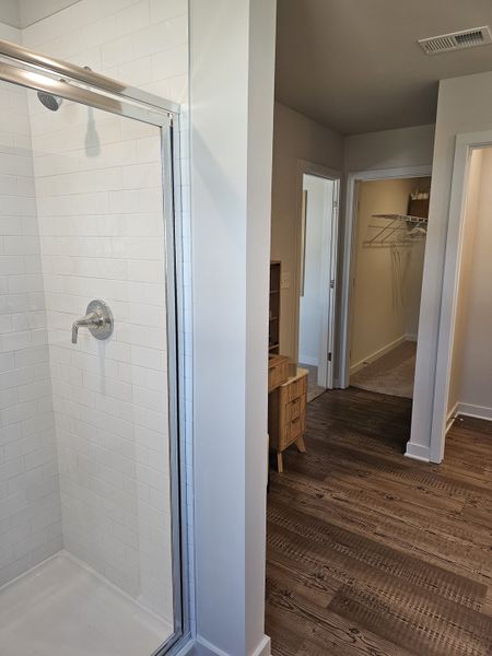 A modern bathroom featuring a sleek glass shower, white tiled walls, and elegant wood flooring. A modern bathroom featuring a sleek glass shower, white tiled walls, and elegant wood flooring.