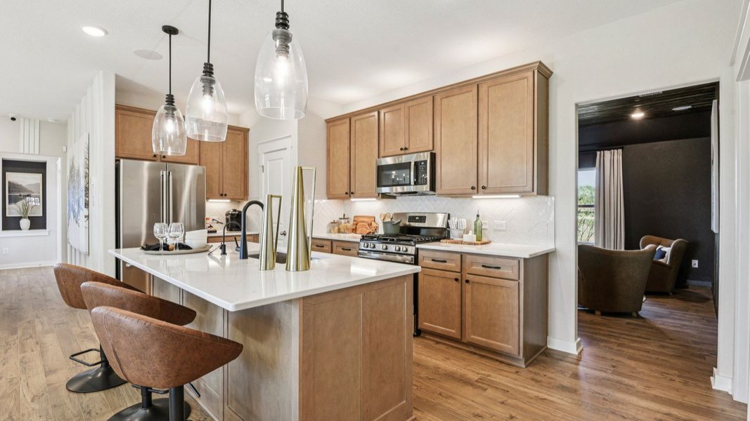 The kitchen features 42 inch wood cabinetry with industrial style pendant lighting above the center island The kitchen features 42 inch wood cabinetry with industrial style pendant lighting above the center island