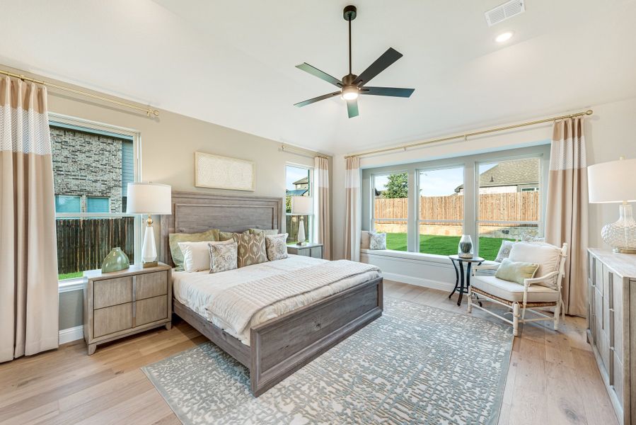 Master bedroom with wood-frame bed, hardwood floors, ceiling fan, and large windows with backyard view Master bedroom with wood-frame bed, hardwood floors, ceiling fan, and large windows with backyard view