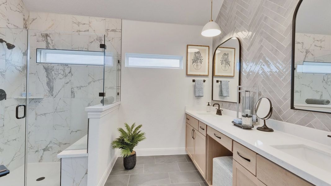 Elegant bathroom featuring marble, herringbone tiles, and dual sinks. Spring Creek community sophistication.