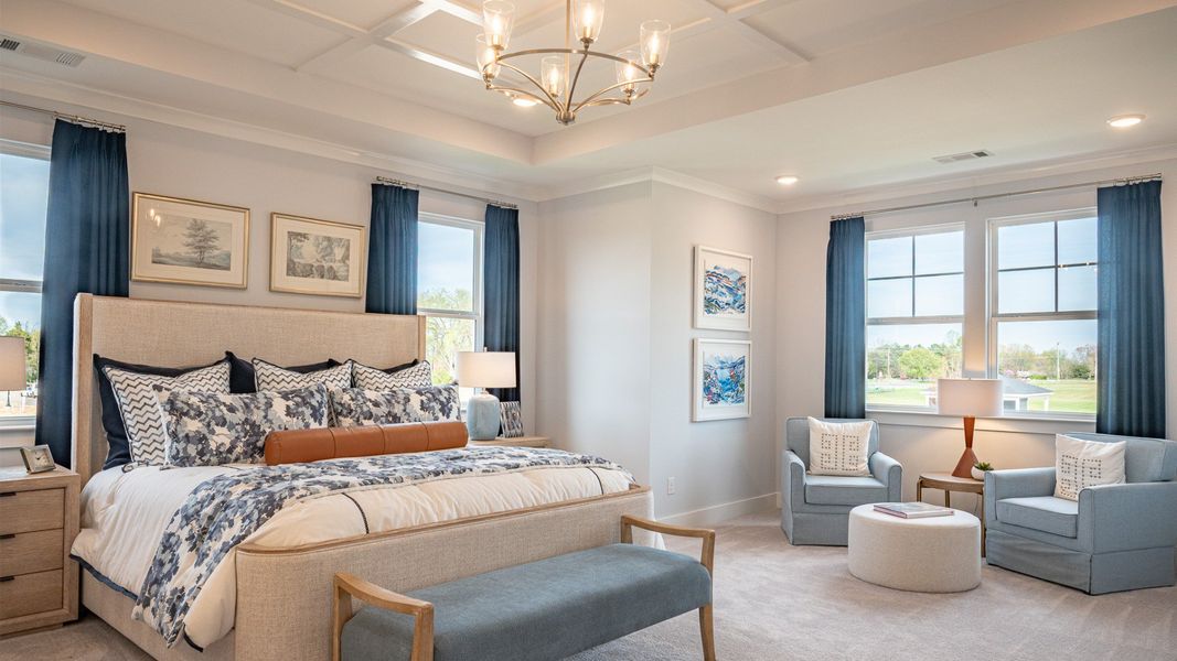 Oversized bedroom with dedicated seating area, accent trim tray ceiling, and king-sized bed