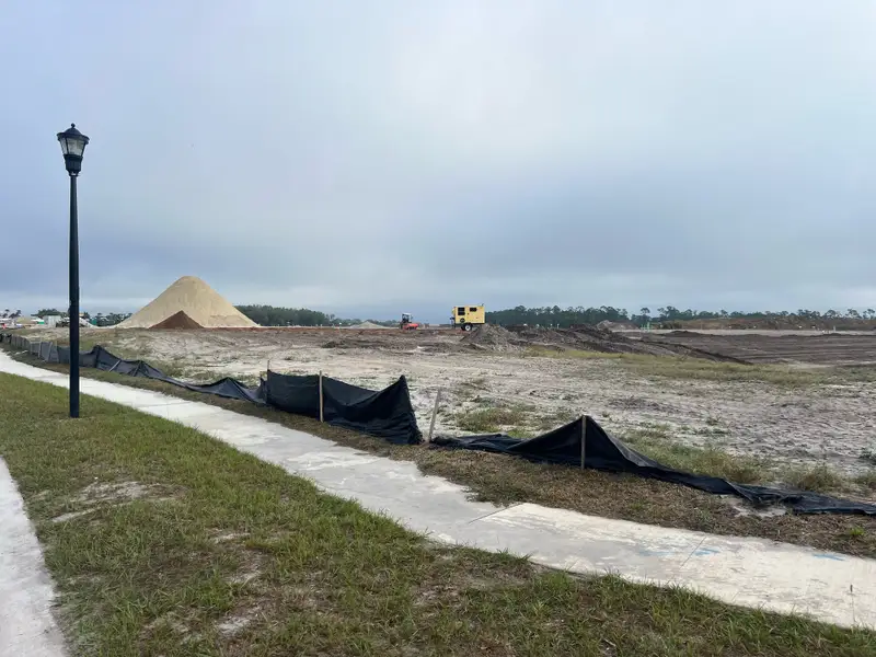 Expansive construction site in Ashton Covey by Ryan Homes, Winter Haven, FL, with vast open land and machinery.
