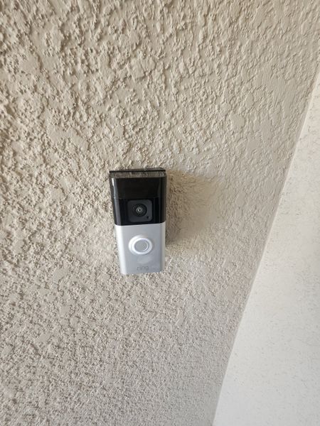 A textured wall featuring a sleek, modern video doorbell for enhanced security.