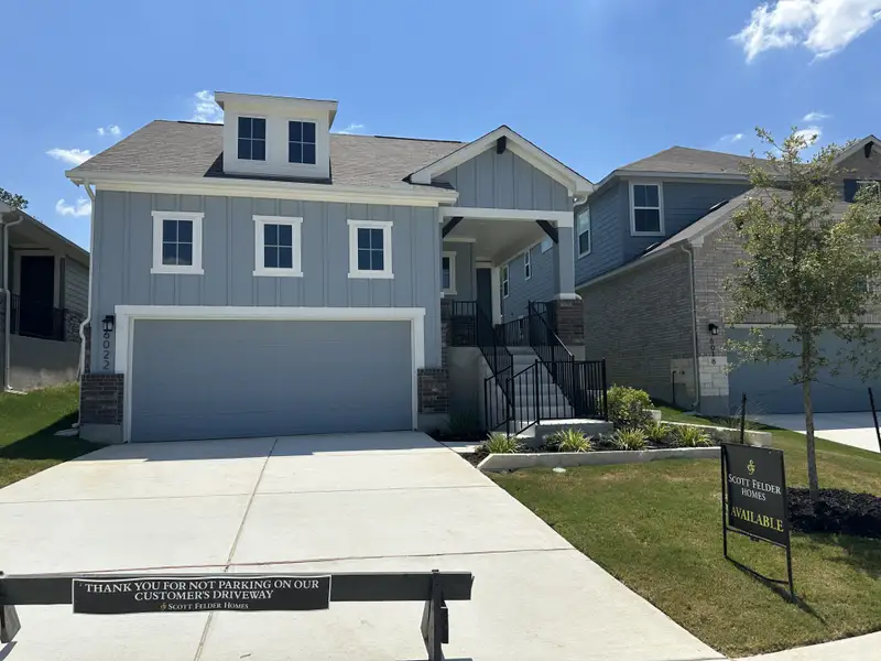 A modern grey home with a spacious driveway and landscaped front yard in Avondale by Scott Felder Homes (San Antonio, TX).
