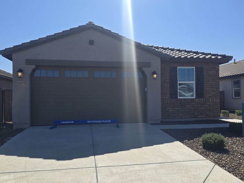 A charming home with brick accents and sleek shutters in Anderson Farms: Premier by Lennar (Maricopa, AZ).