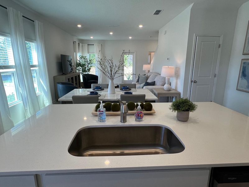 A modern open-concept living area featuring a sleek kitchen island, dining table, and cozy seating with ample natural light.