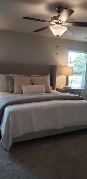 A cozy bedroom featuring a plush bed, neutral decor, and a ceiling fan for comfort and relaxation.