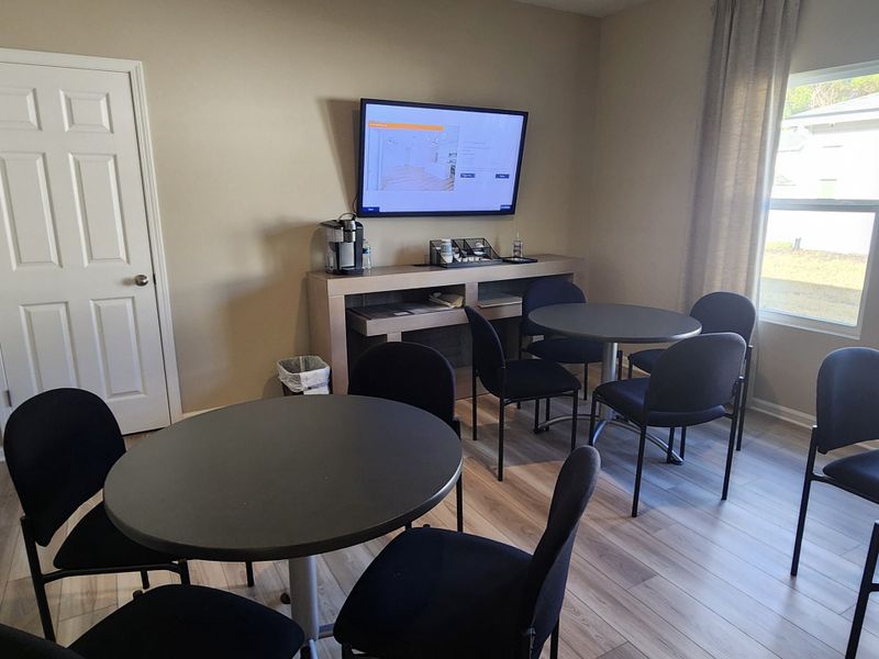 A cozy meeting room with round tables, a wall-mounted TV, and modern decor.