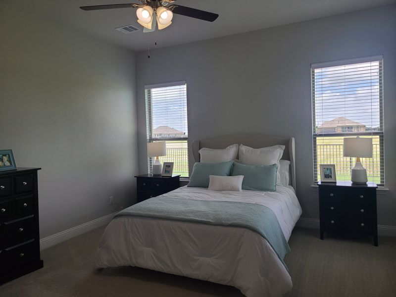 A cozy bedroom featuring a plush bed with soft teal accents, two bedside tables, and a ceiling fan for comfort. A cozy bedroom featuring a plush bed with soft teal accents, two bedside tables, and a ceiling fan for comfort.