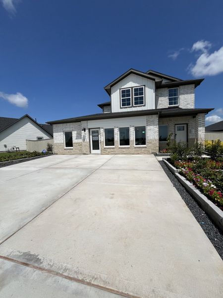 A beautiful two-story home with a spacious driveway and vibrant garden in Lakes at Westland Ranch by D.R. Horton (League City, TX).