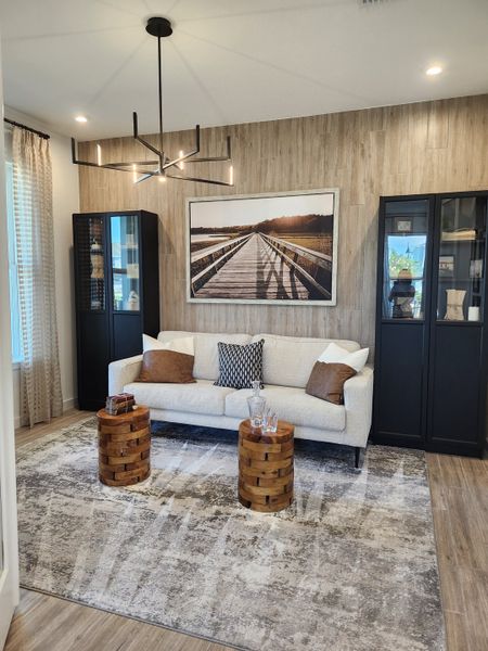 A modern living room featuring a sleek sofa, unique wooden stools, and elegant black cabinets with a stylish chandelier.