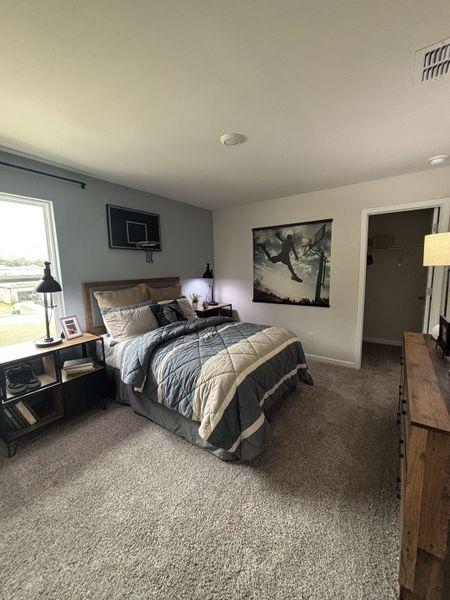 A cozy bedroom features a stylish basketball theme, plush carpeting, and modern furnishings.