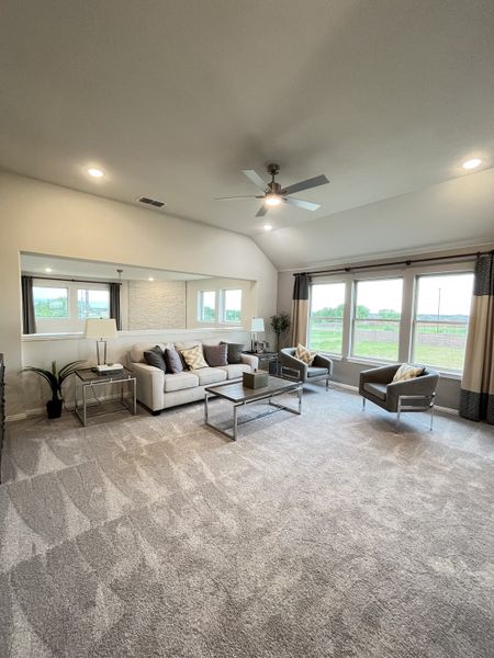 A spacious living room featuring plush carpet, modern furniture, and large windows with scenic views.