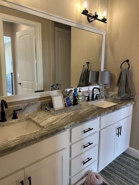 Elegant bathroom with dual sinks, granite countertops, sleek black fixtures, and contemporary lighting. Elegant bathroom with dual sinks, granite countertops, sleek black fixtures, and contemporary lighting.