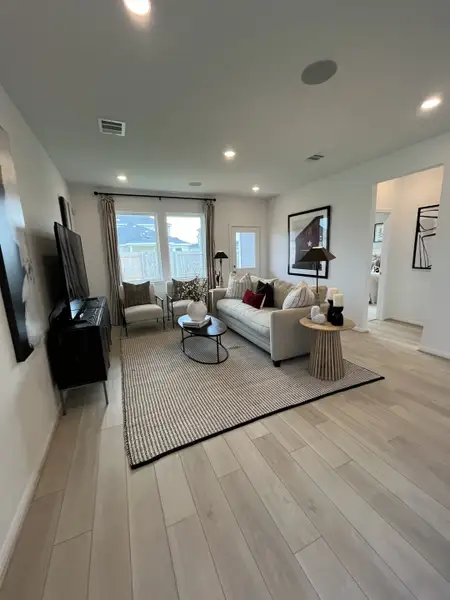A cozy living room with a plush sofa, sleek TV stand, and soft lighting on a striped rug. A cozy living room with a plush sofa, sleek TV stand, and soft lighting on a striped rug.