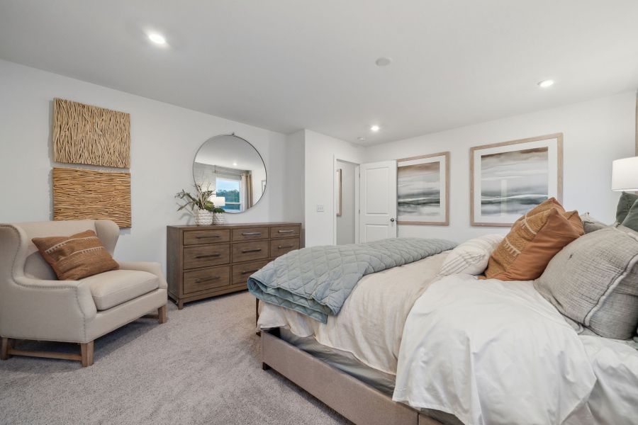 A bedroom with a bed and a chair.