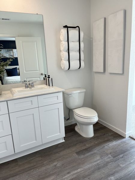 A sleek bathroom with white cabinetry, rolled towels, and light wood flooring for a refreshing feel.