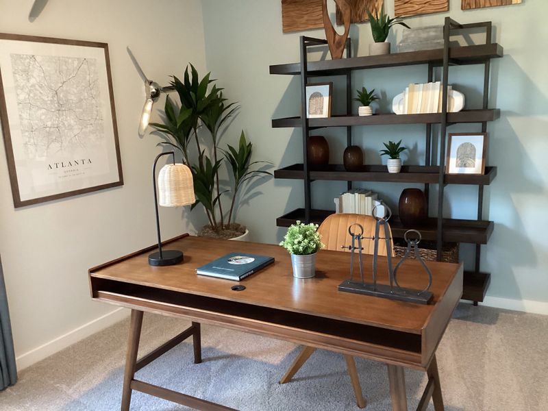 A modern office with a sleek wood desk, open shelving, and decor accents, featuring a city map on the wall.