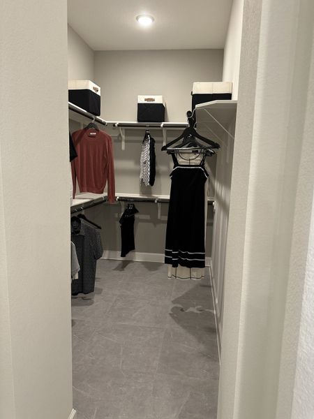 A spacious walk-in closet featuring neutral tones, sleek shelving, and modern lighting for organized storage.