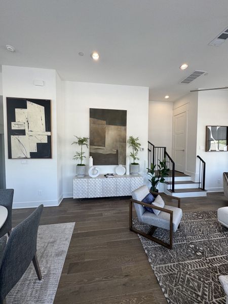 A modern living area featuring abstract art, a textured console, stylish seating, and a patterned rug on wood flooring. A modern living area featuring abstract art, a textured console, stylish seating, and a patterned rug on wood flooring.
