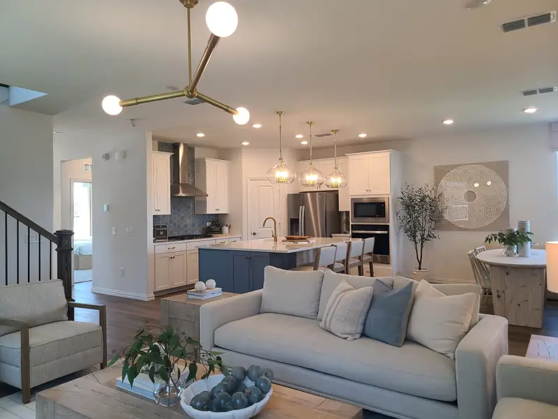 An elegant open-plan living area with modern kitchen, cozy seating, and stylish lighting, enhanced by natural elements.