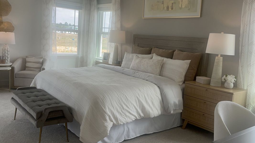 A serene bedroom featuring a plush bed, stylish lighting, and soft neutral tones.