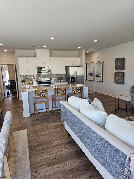 An inviting open-concept living area with elegant hardwood floors, modern kitchen, and cozy seating. An inviting open-concept living area with elegant hardwood floors, modern kitchen, and cozy seating.