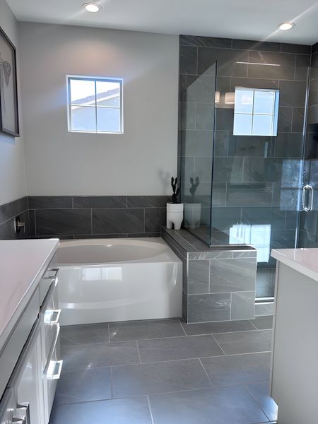 A modern bathroom featuring a sleek tub, glass shower, and elegant gray tiles. A modern bathroom featuring a sleek tub, glass shower, and elegant gray tiles.