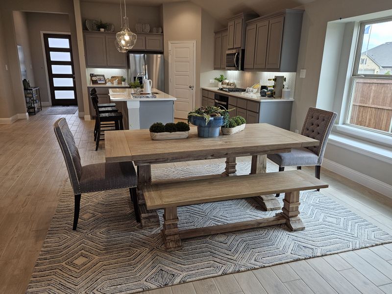 A modern kitchen and dining area featuring wooden floors, a rustic table, sleek cabinets, and ambient lighting. A modern kitchen and dining area featuring wooden floors, a rustic table, sleek cabinets, and ambient lighting.