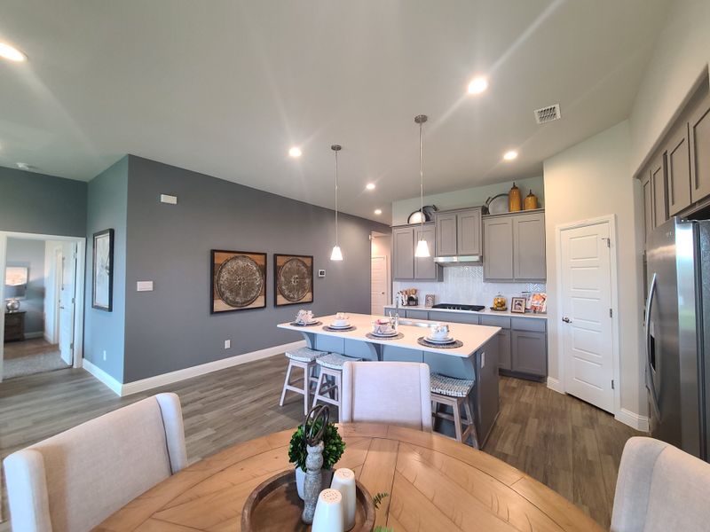 A modern kitchen and dining area with gray cabinets, pendant lighting, and wood-style flooring create a cozy ambiance. A modern kitchen and dining area with gray cabinets, pendant lighting, and wood-style flooring create a cozy ambiance.