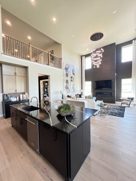 A modern living area with a sleek black kitchen island, soaring ceilings, and a stylish chandelier. A modern living area with a sleek black kitchen island, soaring ceilings, and a stylish chandelier.