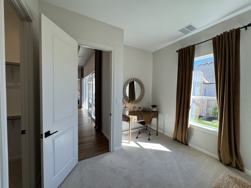 A cozy home office space with a stylish desk, mirror, and soft brown curtains, filled with natural light.