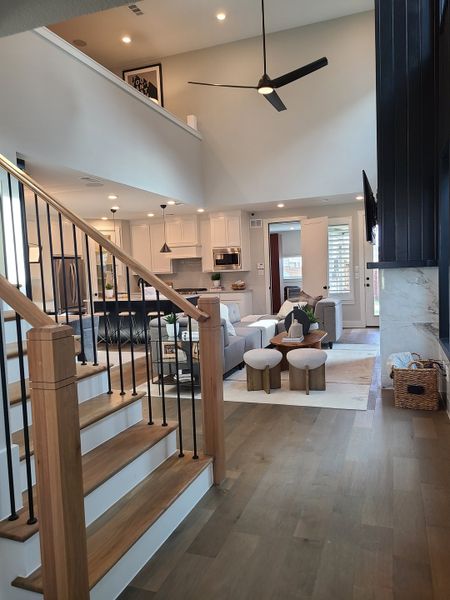 An open-concept living area with sleek stairs, modern fixtures, and cozy seating, accented by high ceilings and natural light.