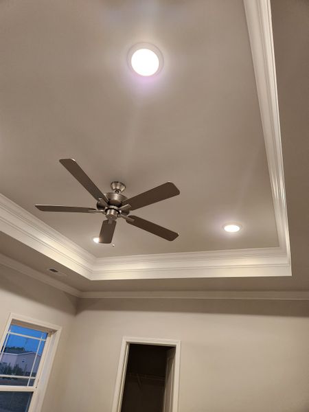 A modern room features recessed lighting, a sleek ceiling fan, and elegant crown molding for a sophisticated touch.