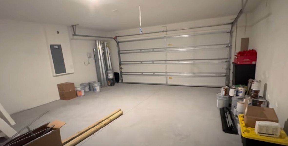 A spacious, organized garage with gray flooring, ample storage, and a modern overhead door.