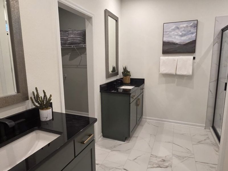 A chic bathroom with dual black vanities, marble floors, and modern decor.