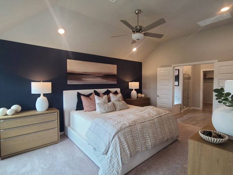 A cozy bedroom with a navy accent wall, modern ceiling fan, and soft lighting, featuring a spacious walk-in closet. A cozy bedroom with a navy accent wall, modern ceiling fan, and soft lighting, featuring a spacious walk-in closet.