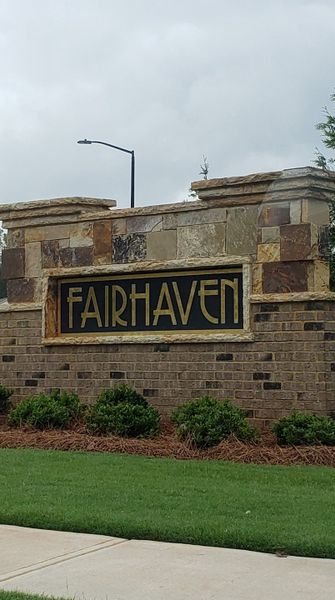 A welcoming stone entrance with landscaped greenery at Fairhaven by D.R. Horton (Lithia Springs, GA).