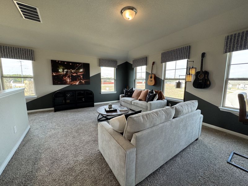 A cozy living room with plush sofas, wall-mounted guitars, and large windows, offering ample natural light and style.