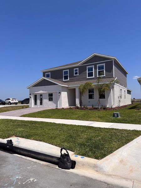 A modern two-story home with a lush lawn in Wellness Ridge: Manor Collection by Lennar (Clermont, FL).