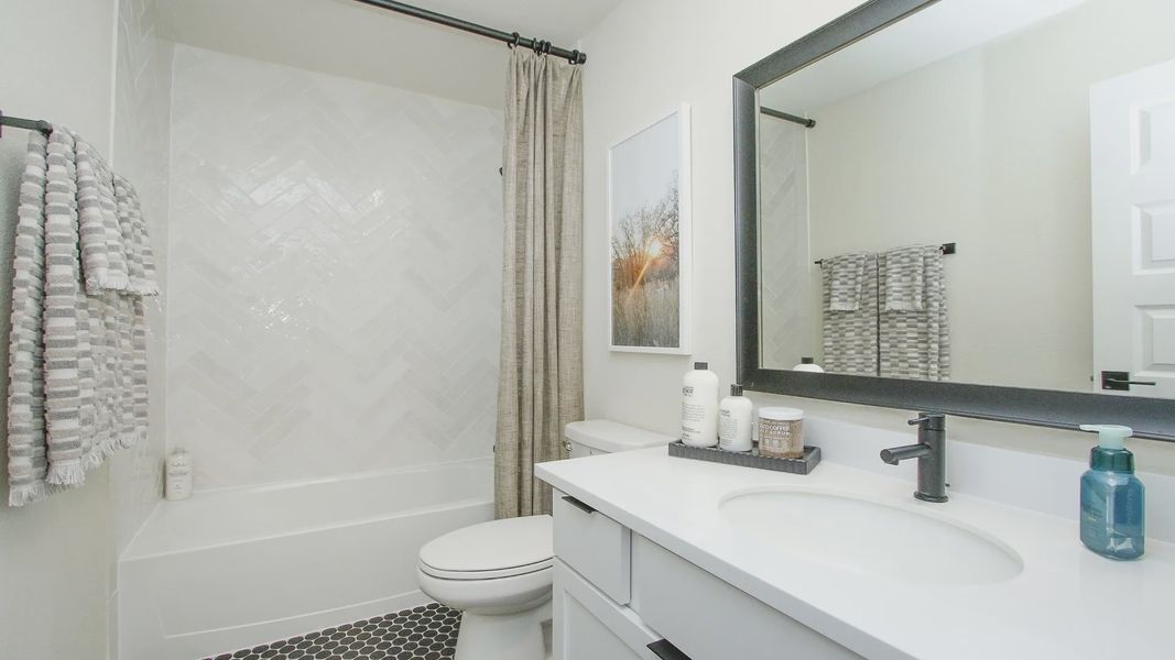 Featuring exquisite herringbone tile and sleek fixtures, this bathroom epitomizes luxury at Colony at Pinehurst.