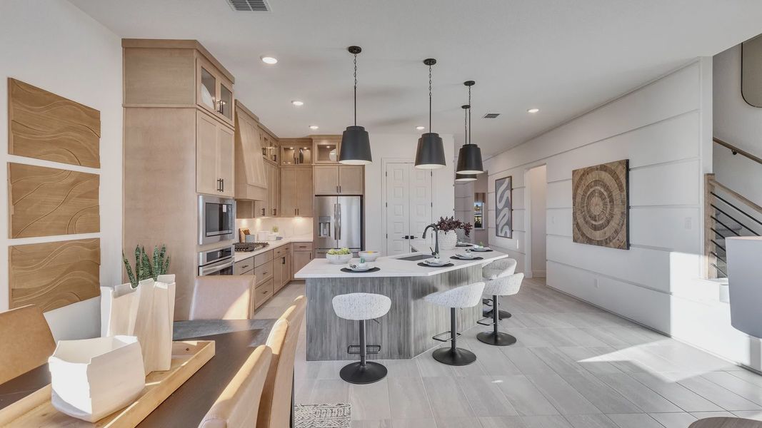 Elegant kitchen features light wood cabinetry, sleek island, and luxury finishes in Creeks Crossing.