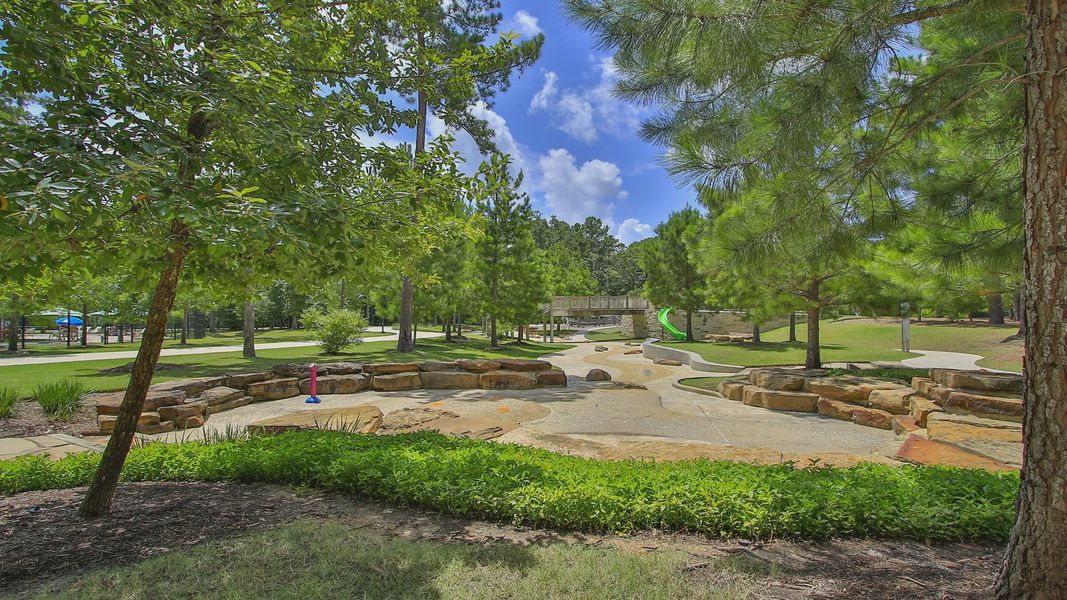Embrace nature at The Woodlands Hills with stone pathways, lush greenery, and serene play areas.
