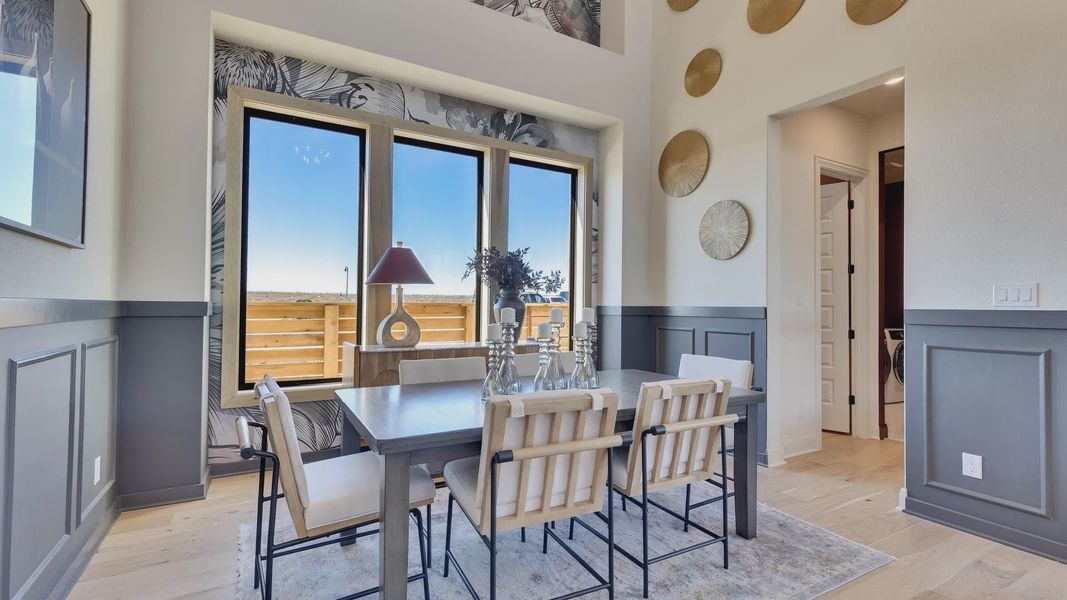 Elegant dining room with expansive windows and chic wainscoting, offering panoramic views in Flora community.