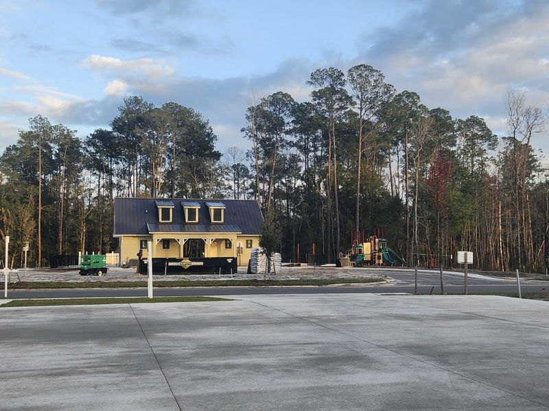 A charming yellow house with dormer windows surrounded by trees in Jennings Farm by Dream Finders Homes (Middleburg, FL).