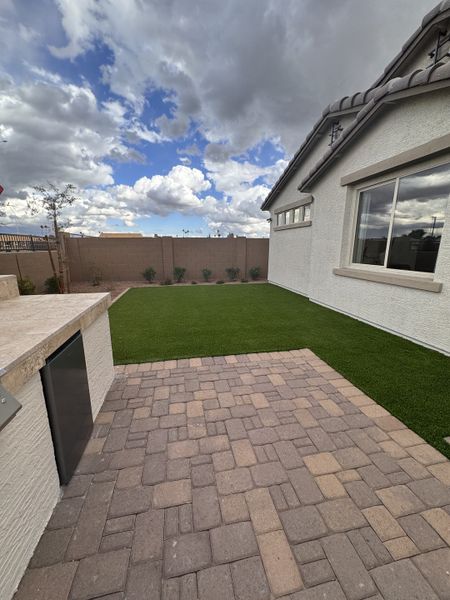 A pristine backyard with a modern patio and lush lawn in Seasons at Trevino by Richmond American Homes (Glendale, AZ).