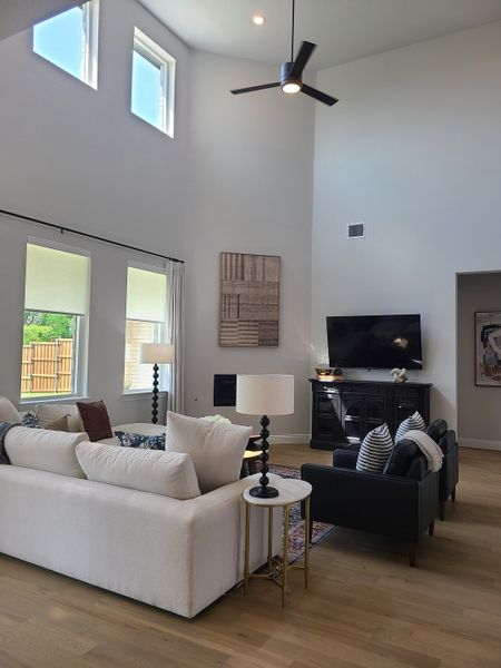 A spacious living room with high ceilings, modern furnishings, large windows, and a neutral palette creating a bright ambiance.