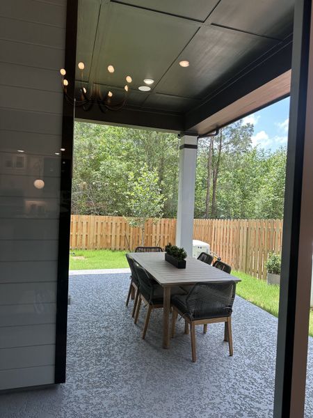 A cozy outdoor patio with dining set, surrounded by a wooden fence and lush greenery. Perfect for relaxed gatherings.