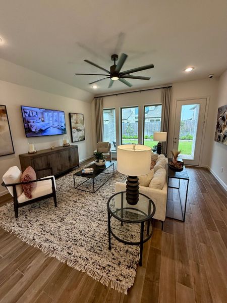 A cozy living room with a textured rug, modern ceiling fan, and sleek furnishings, offering a stylish and inviting atmosphere.