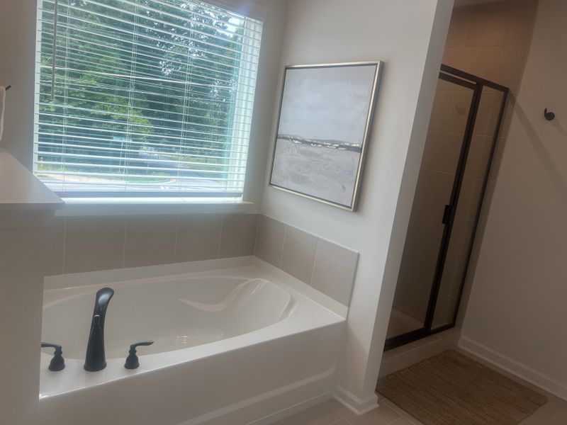 A bright bathroom with a soaking tub, sleek black fixtures, a glass shower, and a large window for natural light. A bright bathroom with a soaking tub, sleek black fixtures, a glass shower, and a large window for natural light.